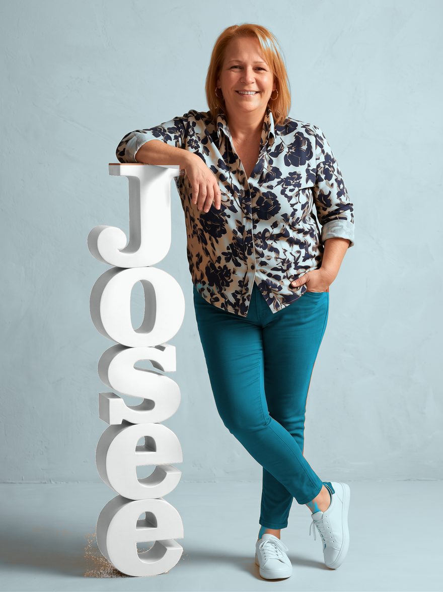 Josée Duteau, souriante, appuyée sur les lettres de son prénom